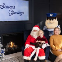 Mom in yellow dress with daughter in red dress on Santa's lap